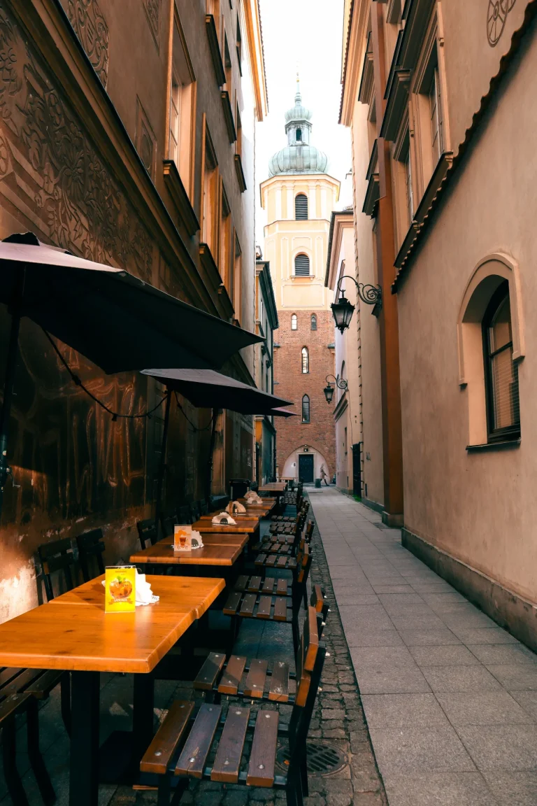 Picturesque alley in Krakow with a view of church and outdoor cafe tables on a sunny day