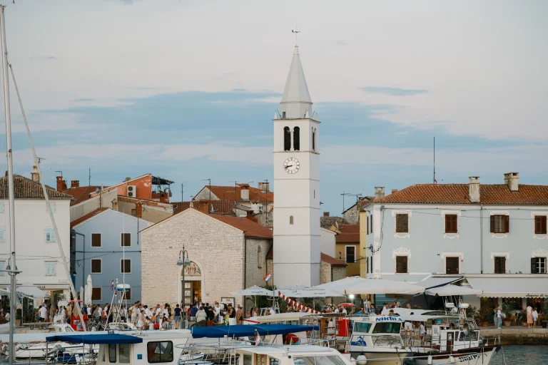 Picturesque Croatian harbor with clock tower and boats at dusk